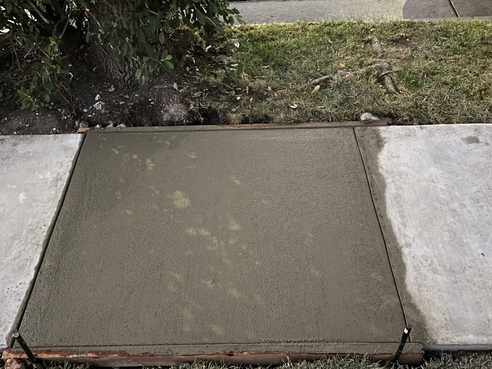Newly poured and floated concrete walkway section, set flush with the existing sidewalk