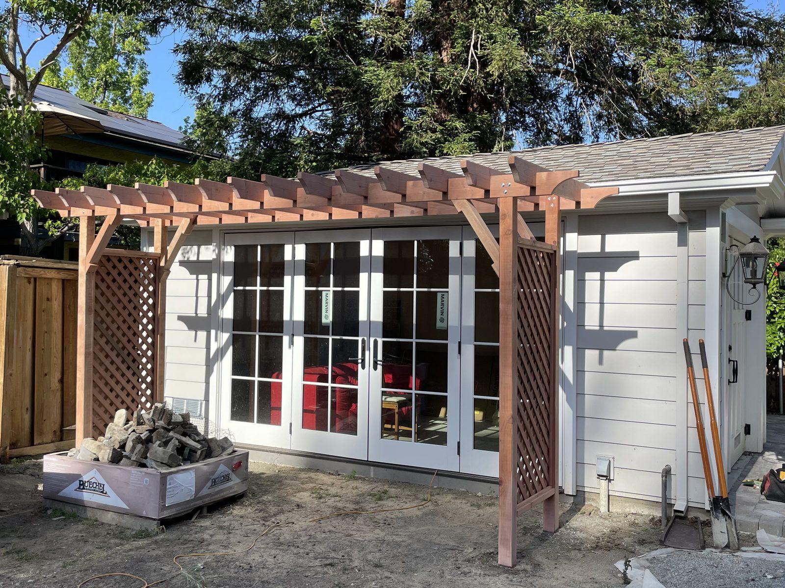 Completed timber patio cover with lattice side screens, framing a set of french doors