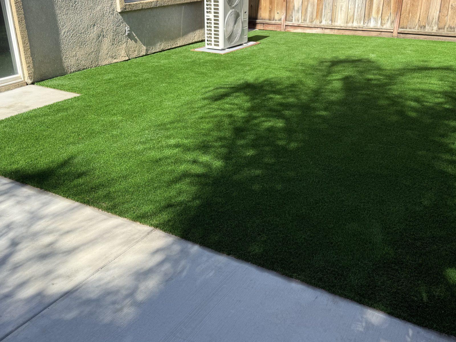 Narrow side yard finished with artificial turf running the length of the fence beside a concrete path